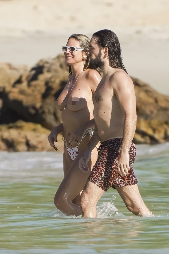 Heidi Klum and Tom Kaulitz walking in the ocean.