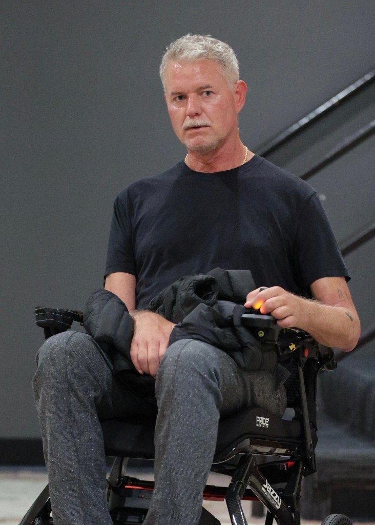 Eric Dane in a motorized wheelchair with a black puffer jacket on his lap.