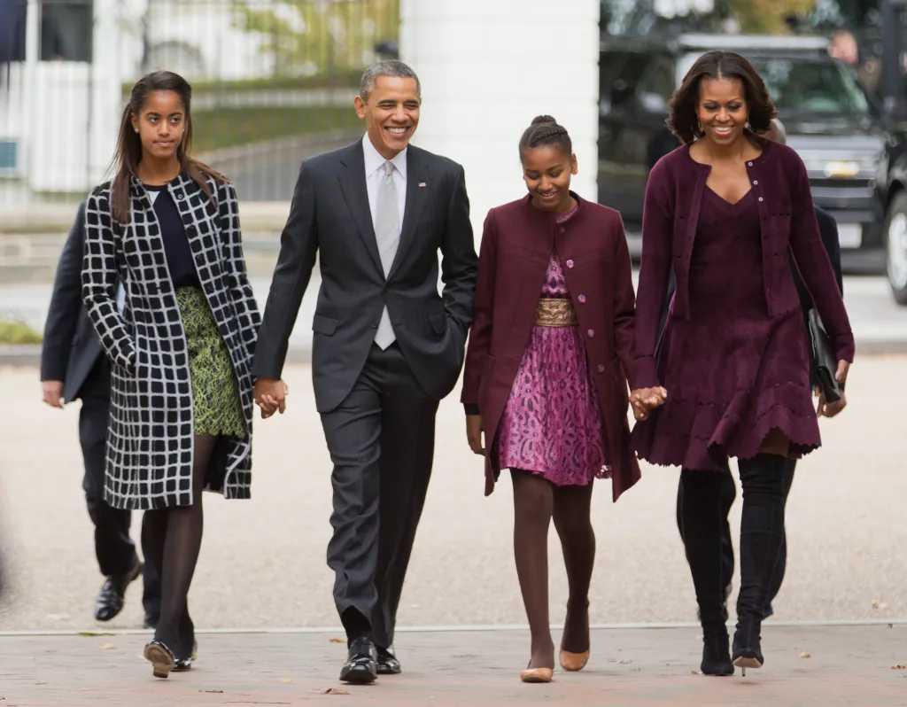 Barack Obama, Michelle Obama, Malia Obama, and Sasha Obama walking together outside.