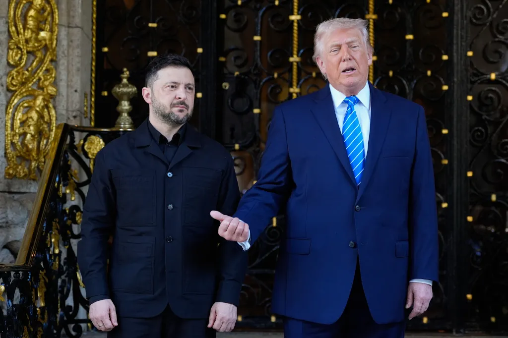 Donald Trump with his hand on Volodymyr Zelenskyy's back while talking, standing in front of an ornate door.