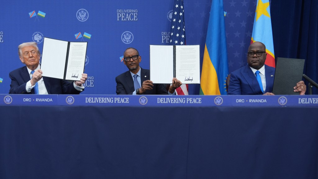 President Donald Trump, President Paul Kagame, and President Felix-Antoine Tshisekedi hold up documents at a signing ceremony.