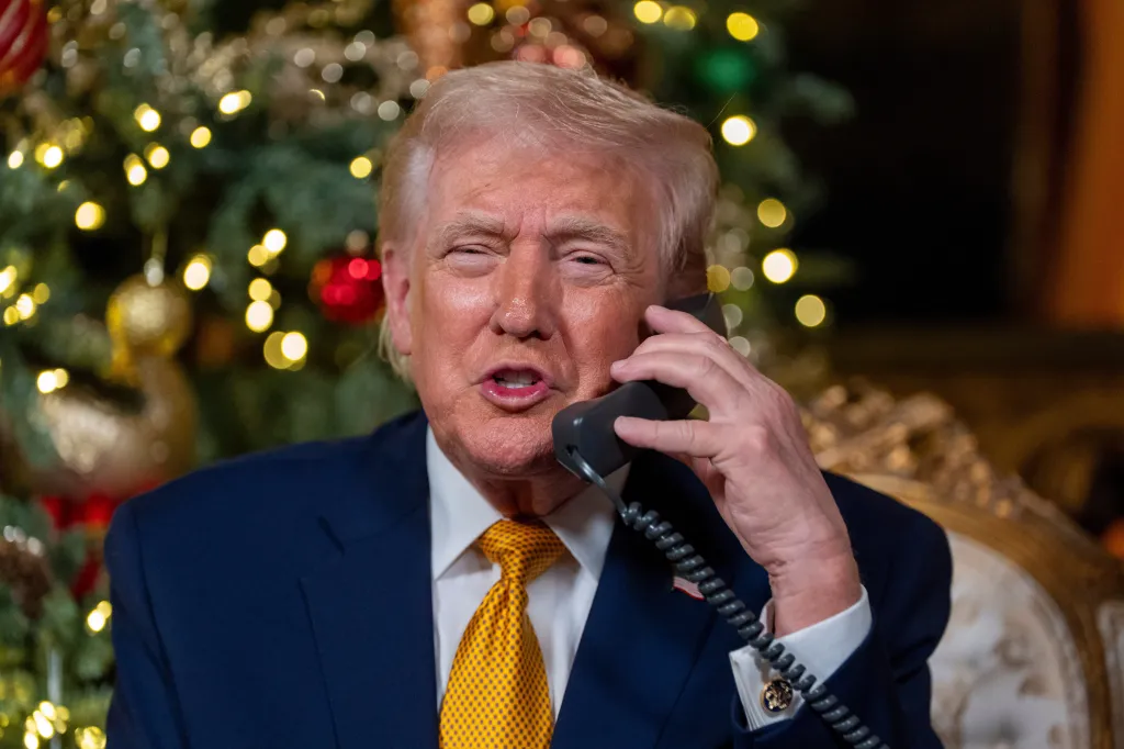 Donald Trump on the phone in front of a Christmas tree.