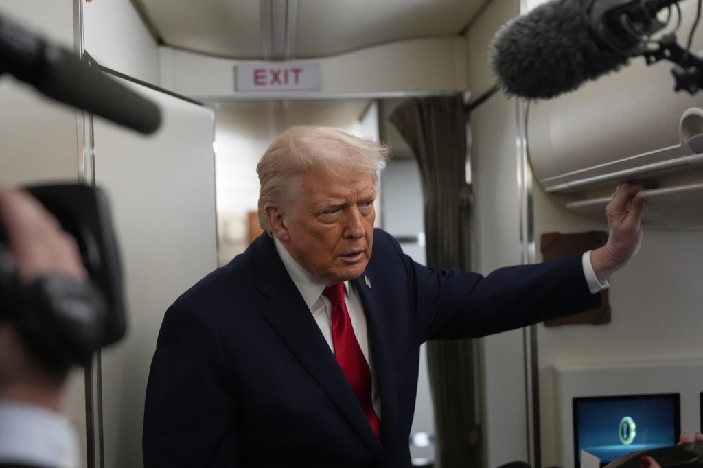 President Donald Trump speaks with reporters while in flight on Air Force One.