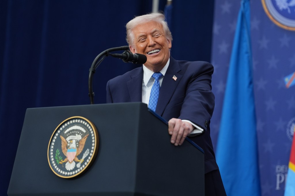 President Donald Trump smiling at a podium.