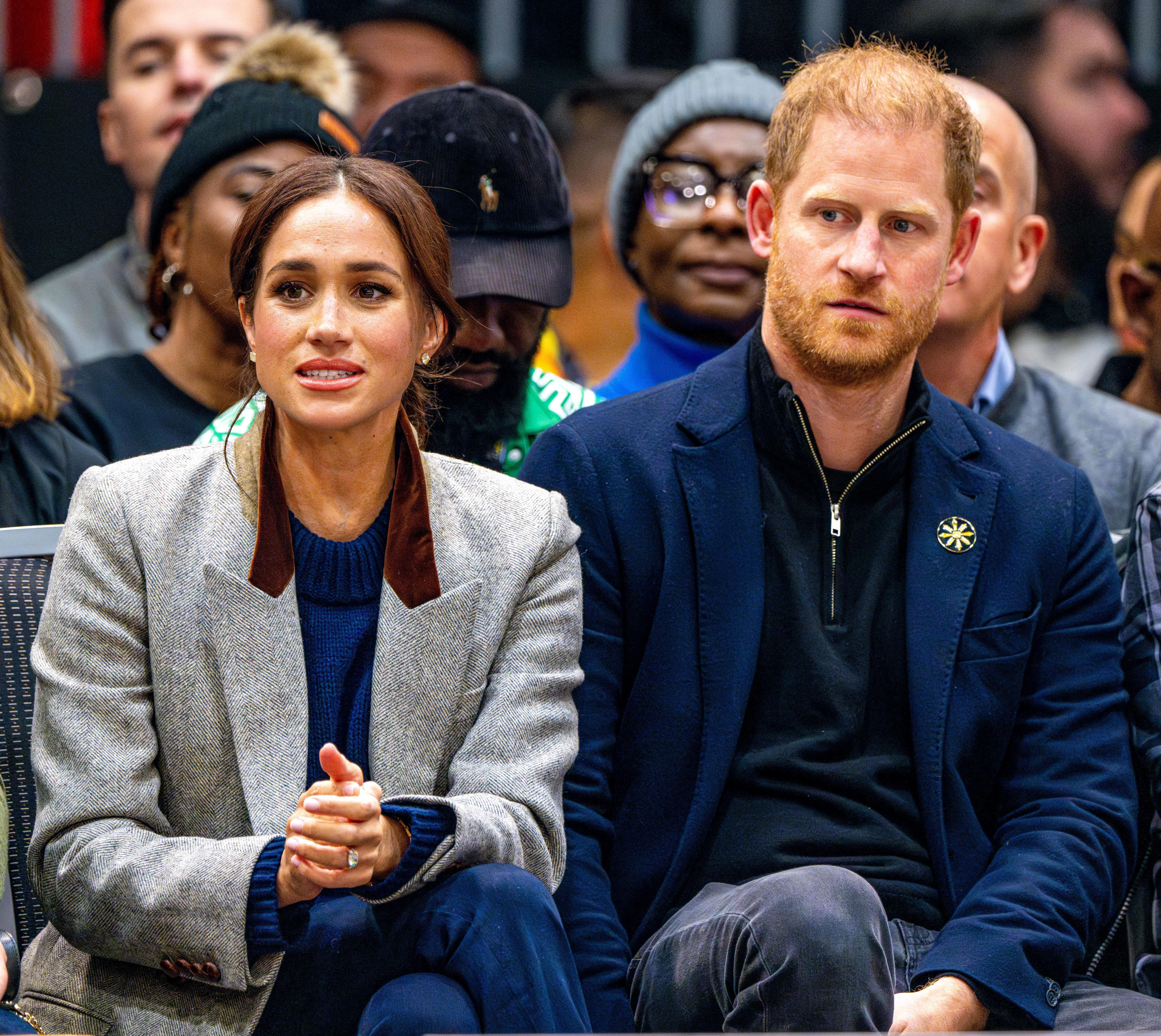 Prince Harry and Meghan Markle sitting together as spectators.
