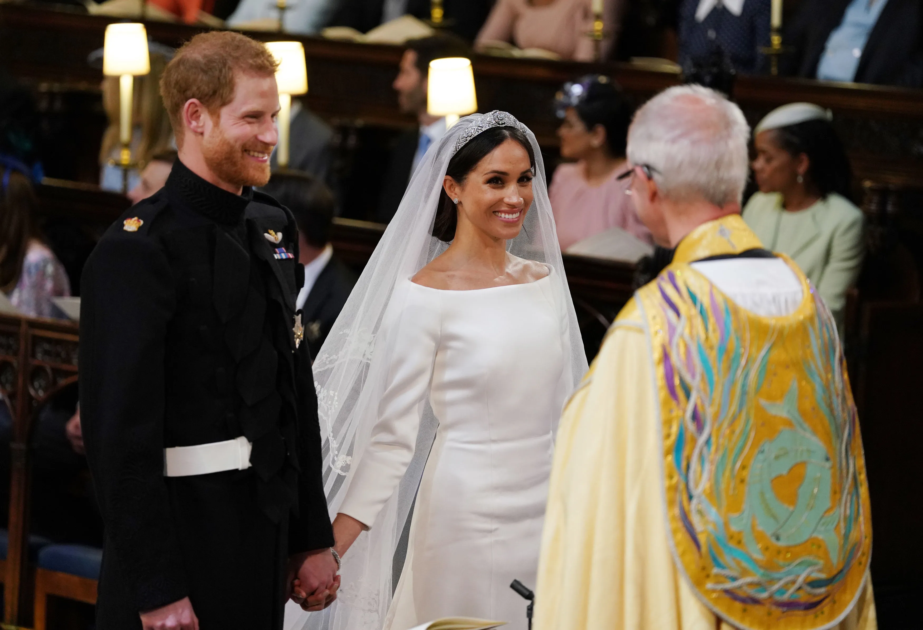Prince Harry and Meghan Markle holding hands during their wedding ceremony, facing the Archbishop of Canterbury Justin Welby.