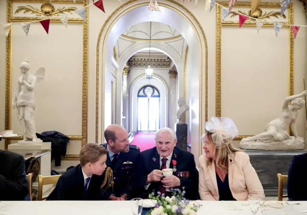 Prince William and a boy interacting with a veteran and a woman at a table.