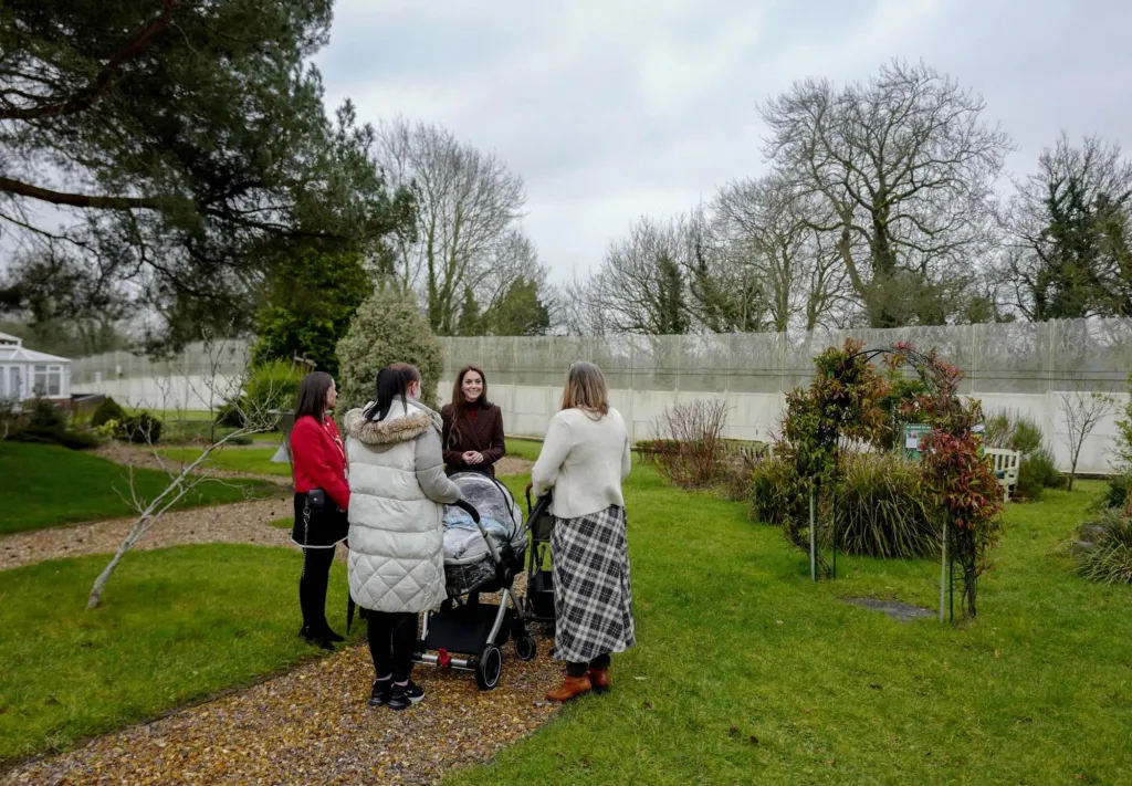 Kate Middleton talking to three women next to a stroller on a gravel path.