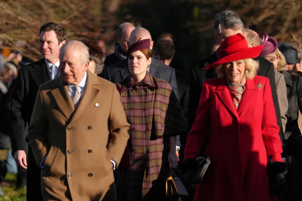King Charles III, Queen Camilla, and Princess Eugenie walking together outdoors.