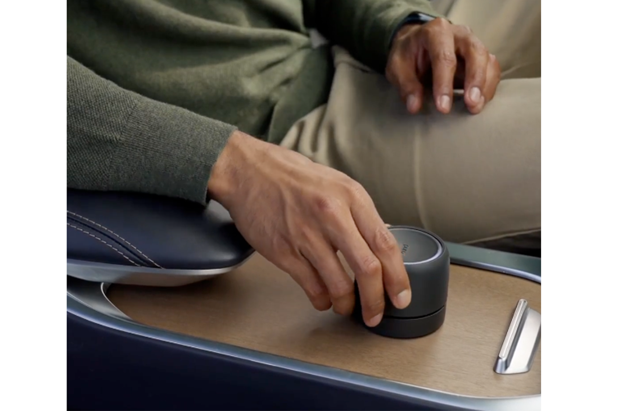 A person turning a black dial on a wooden surface.