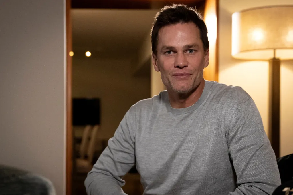 Tom Brady, former NFL quarterback, wearing a gray long-sleeved shirt and looking at the camera.