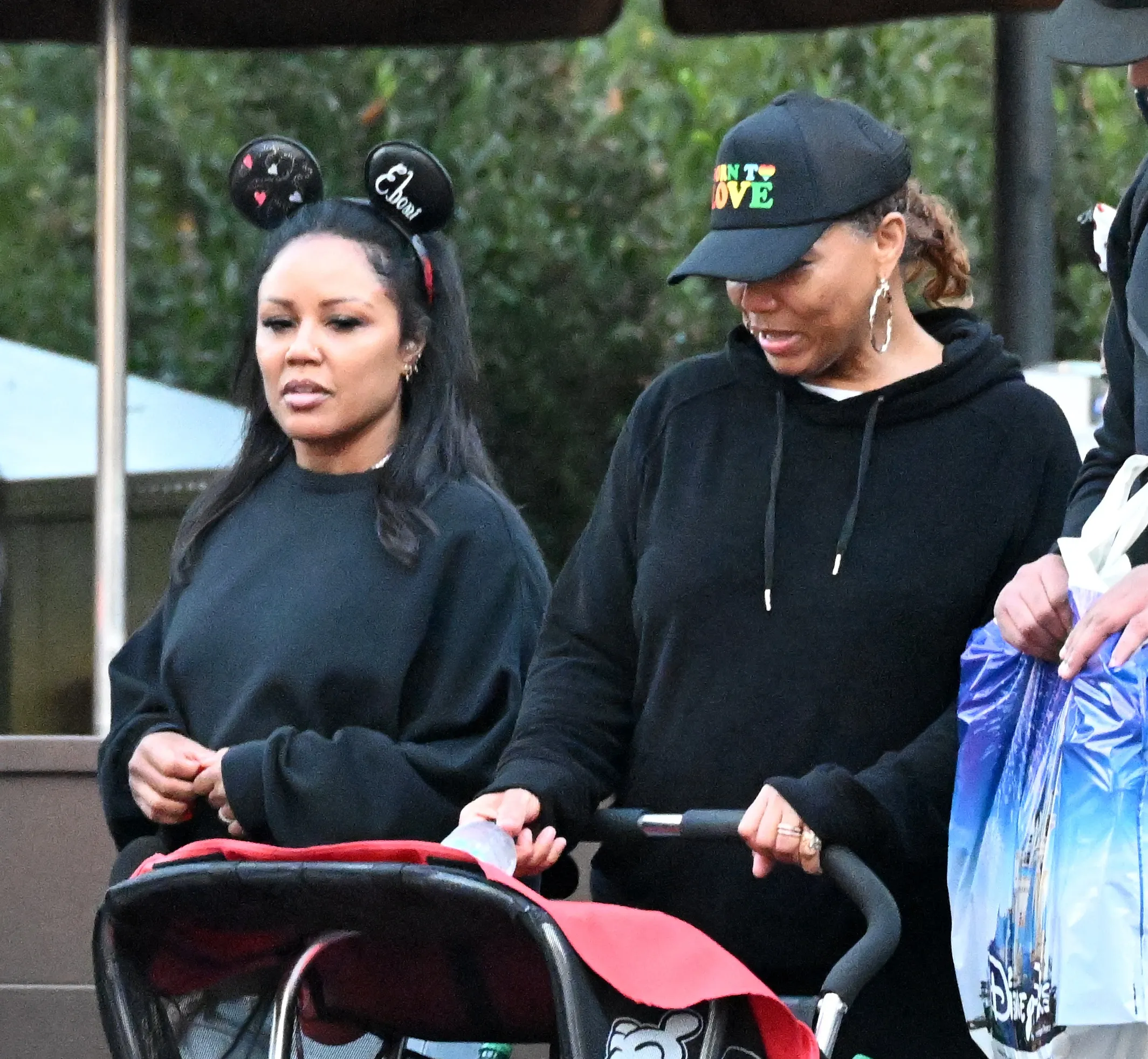 Queen Latifah pushing a stroller and Eboni Nichols walking alongside her at Disneyland.