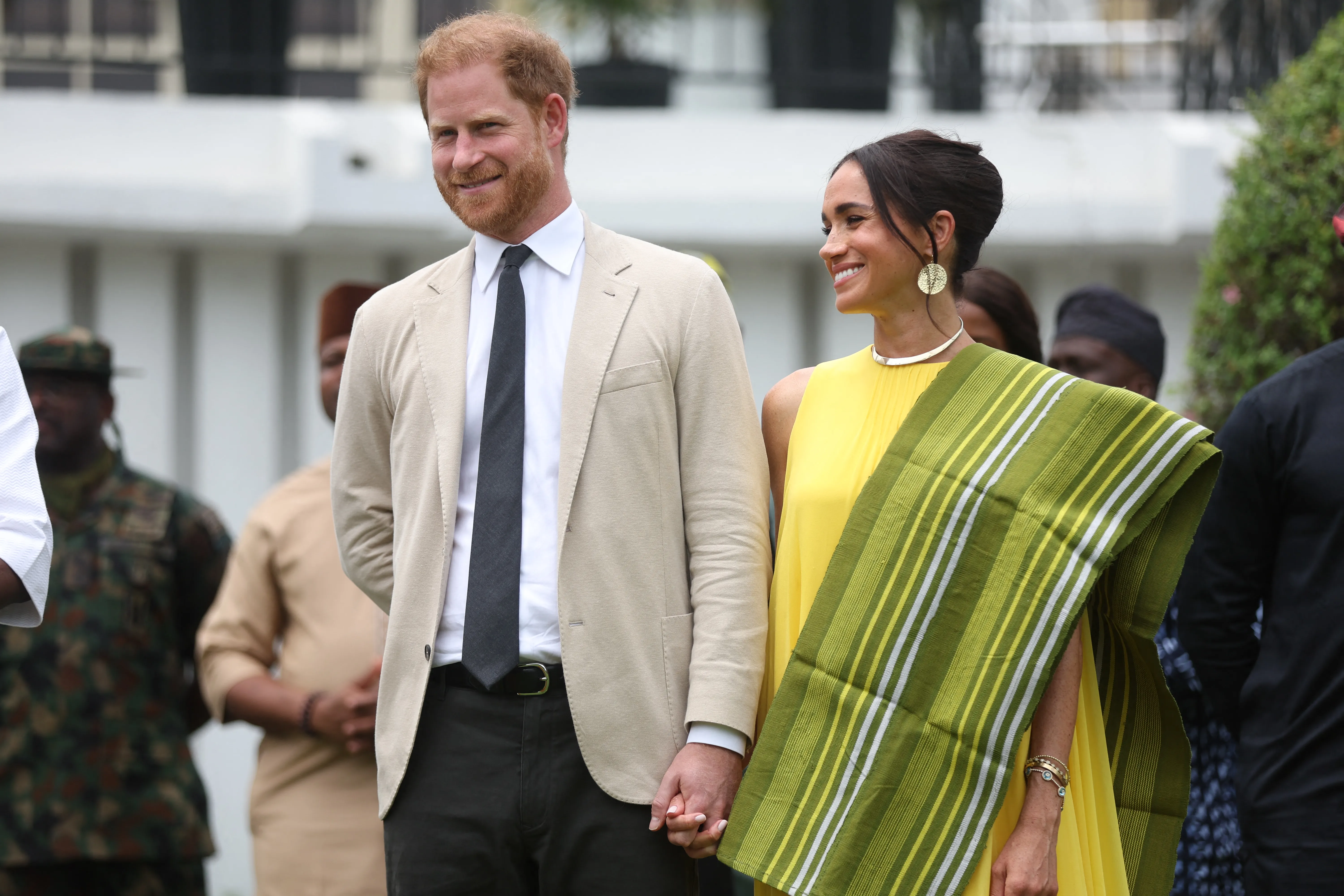 Prince Harry and Meghan Markle react to a speech at the State Governor House in Lagos.