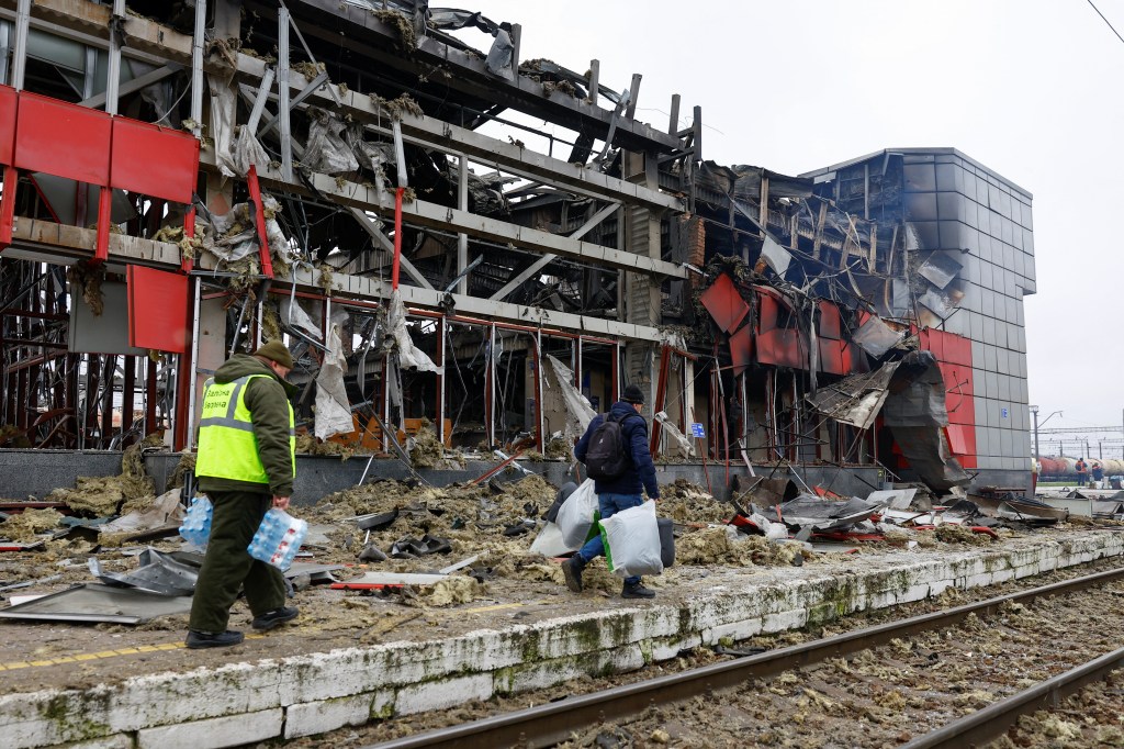 Railway employees carry items next to a station struck in the overnight assault.