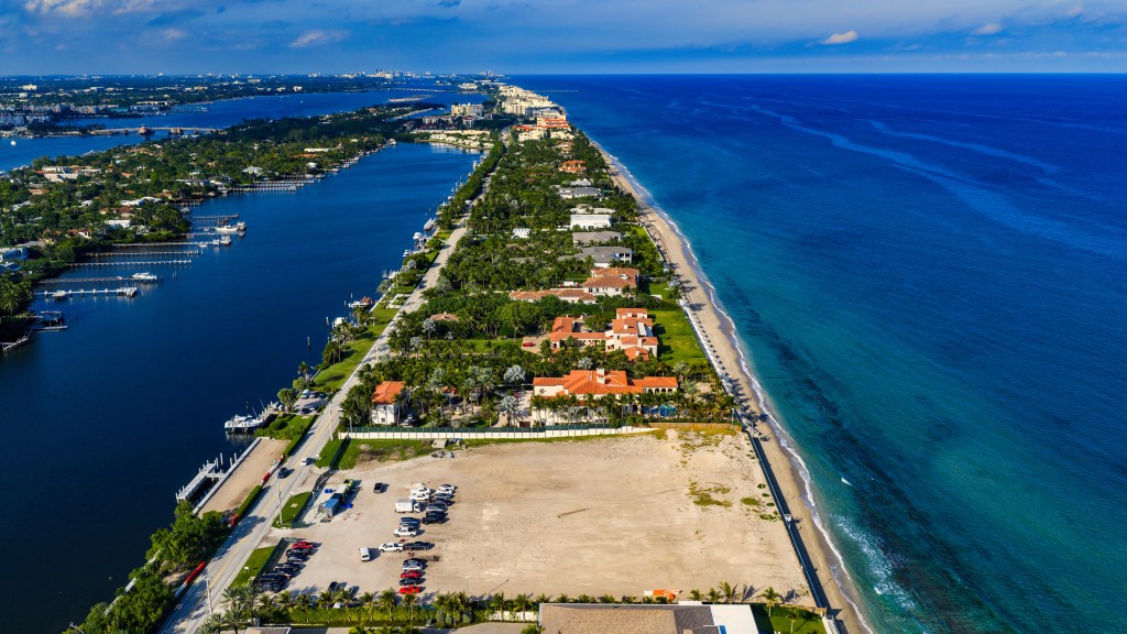 Aerial view of 3.5 acres of land at 1140 S Ocean in Manalapan, surrounded by other properties, with a road and waterway on one side and a beach and the ocean on the other.