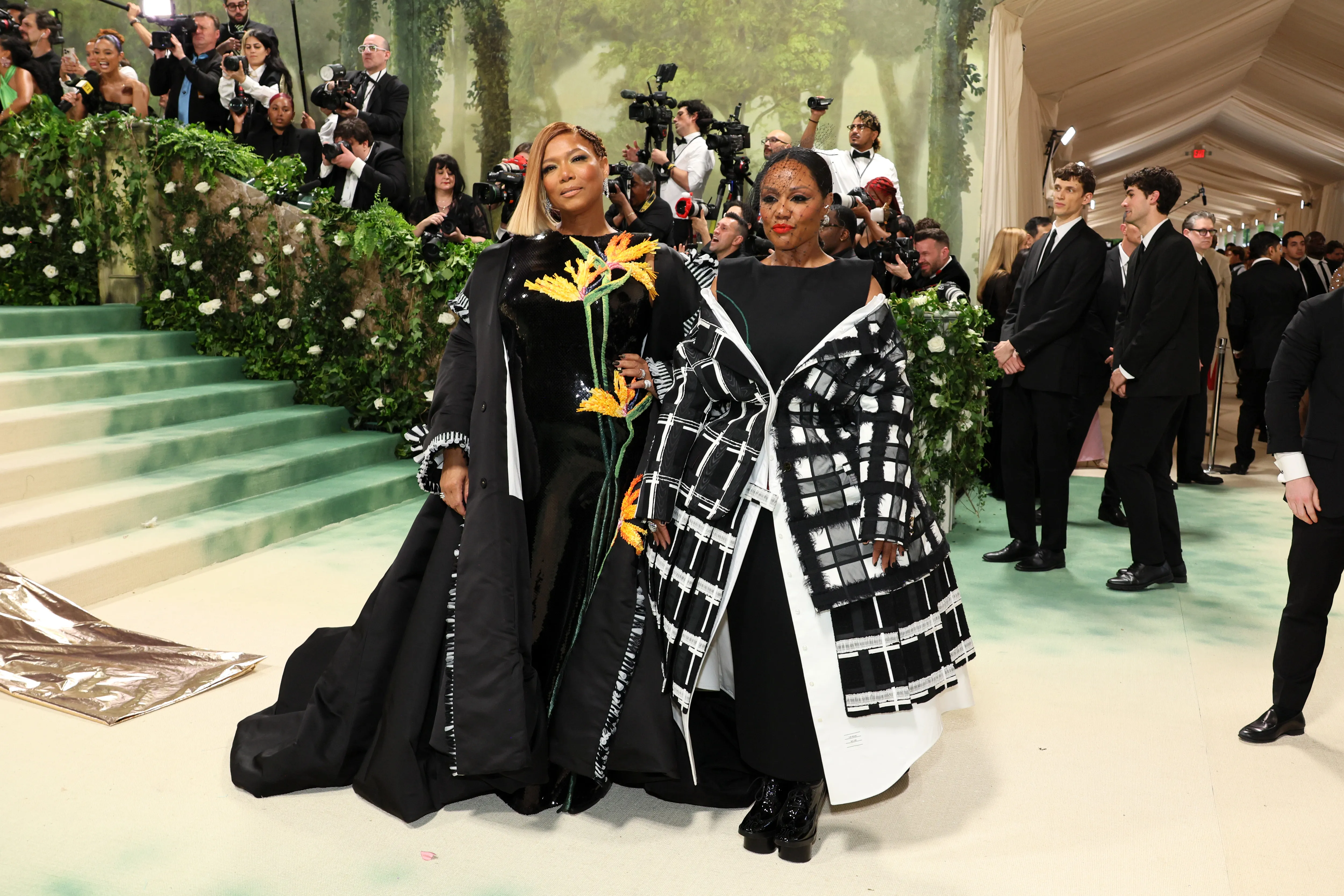 Queen Latifah and Eboni Nichols attending the 2024 Met Gala in custom Thom Browne outfits.