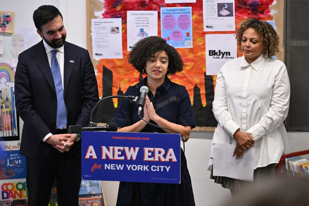 Catherine Da Costa, head of the Mayor’s Office of Appointments, giving remarks at a podium in front of mayor-elect Zorhan Mamdani and union leader Jahmila Edwards.