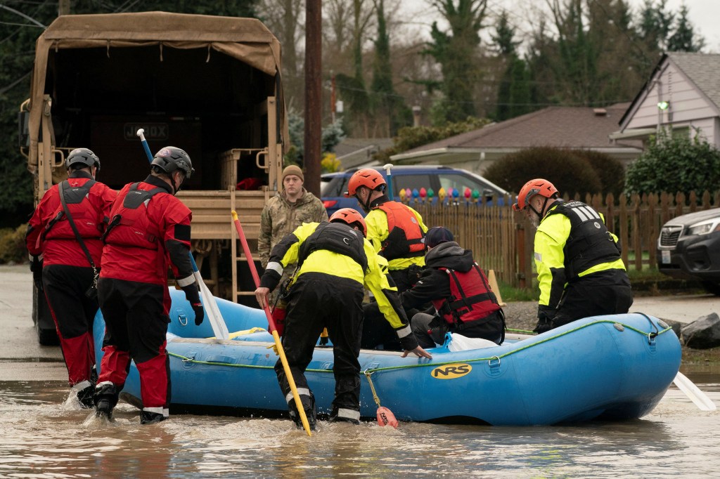 Rescue crews evacuate a person and two dogs in a blue raft from floodwaters in Burlington, Washington.