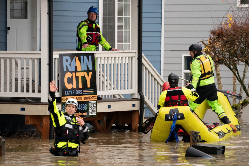 Rescue personnel knock on the doors in a neighborhood flooded by the Snohomish River.