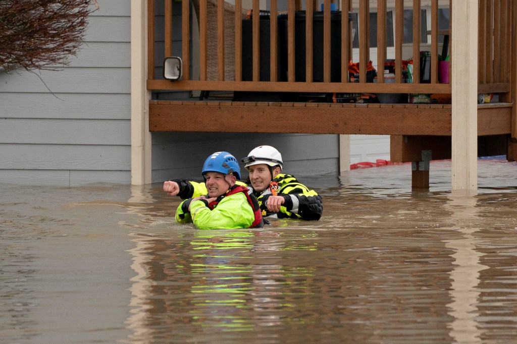 Rescuers wade in flood waters preparing to evacuate residents from a home flooded by the Snohomish Riverin Washington State on Dec. 11, 2025.