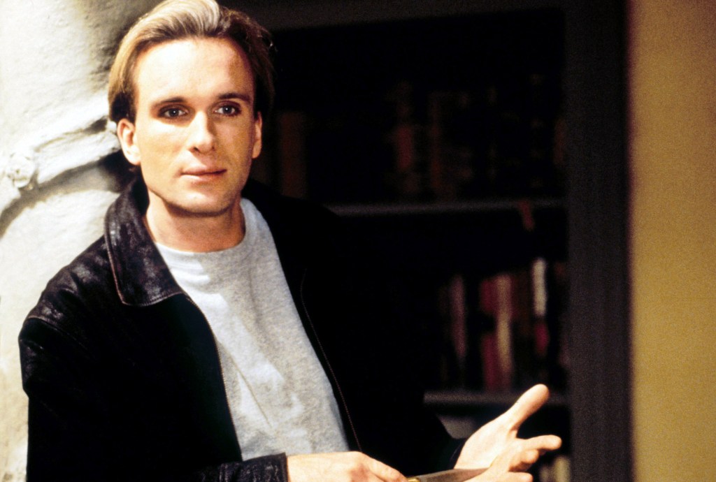 Peter Greene in a leather jacket and grey shirt, with a knife in his hand.