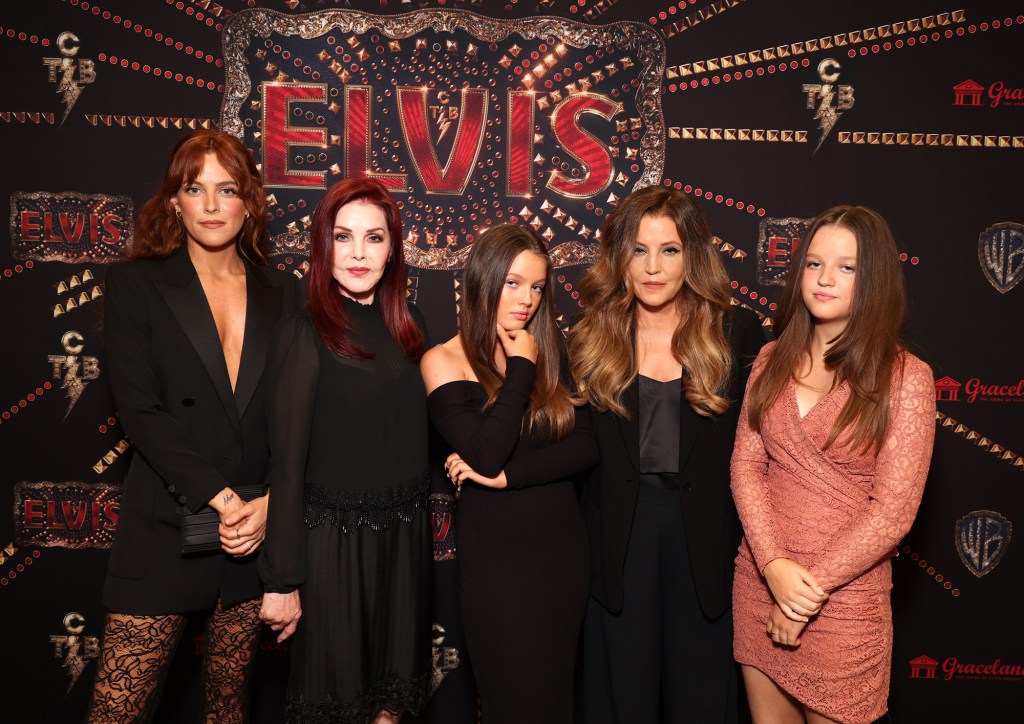 Riley Keough, Priscilla Presley, Harper Vivienne Ann Lockwood, Lisa Marie Presley, and Finley Aaron Love Lockwood pose in front of an 