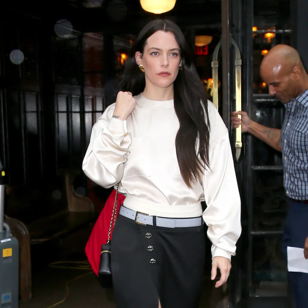 Riley Keough in a cream satin top and black skirt on her way to the Chanel Metiers d'Art 2026 Fashion Show.