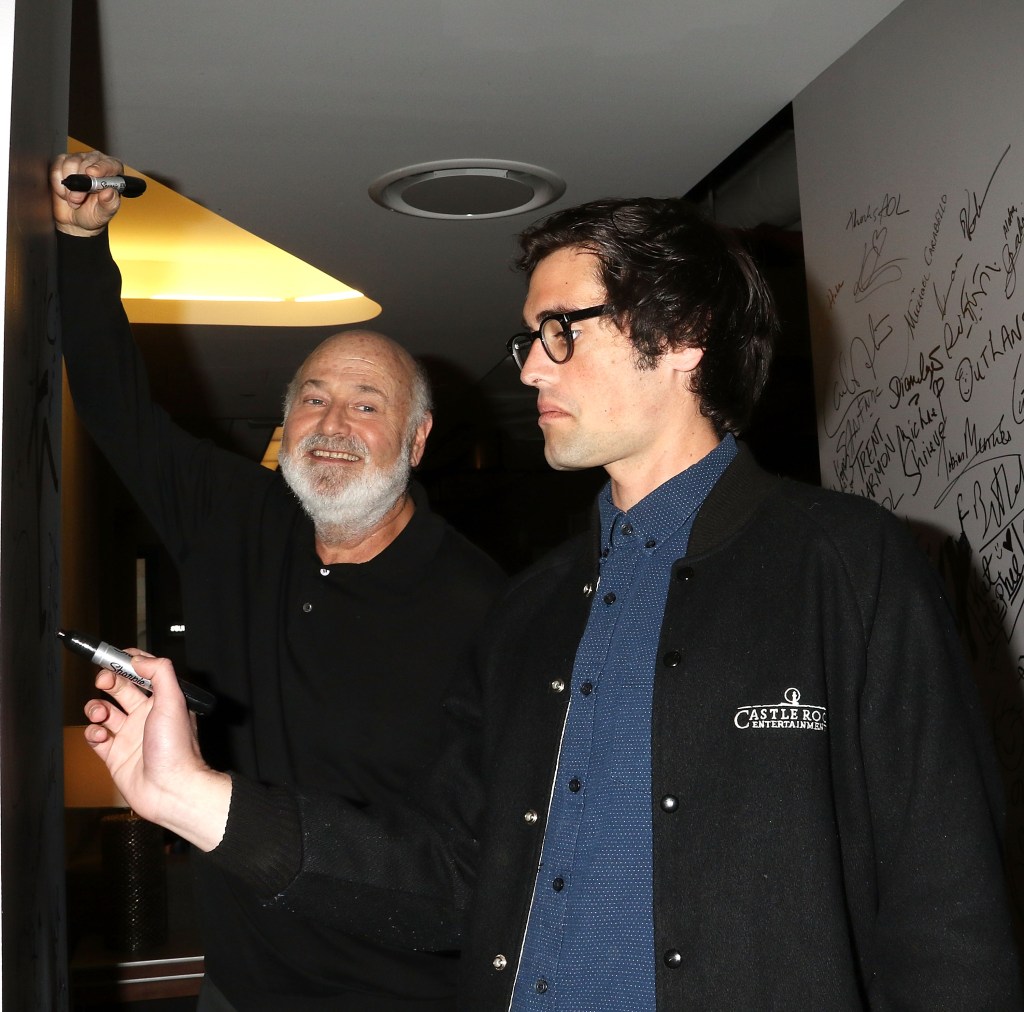 Rob Reiner and Nick Reiner signing a wall with Sharpie markers.