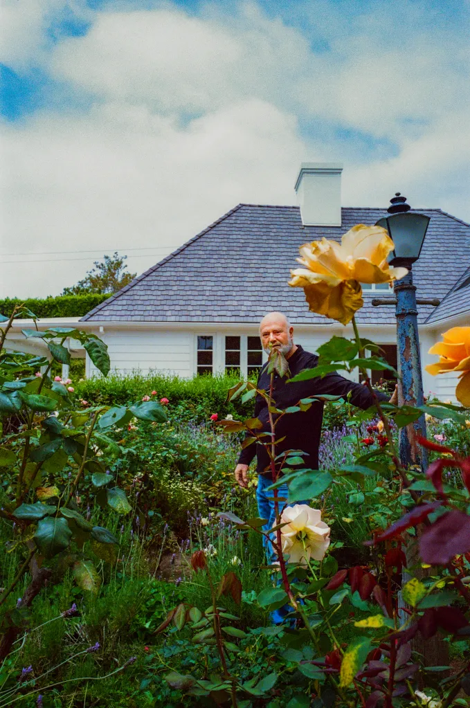 Rob Reiner standing in a garden with a house in the background.