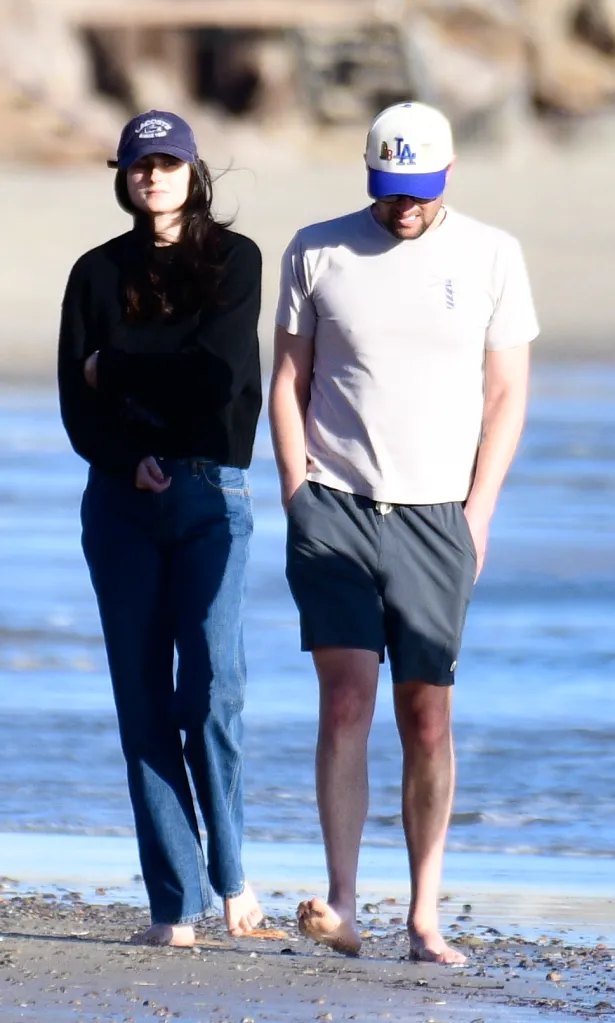 Romy Reiner and Jake Reiner walk barefoot on the beach.
