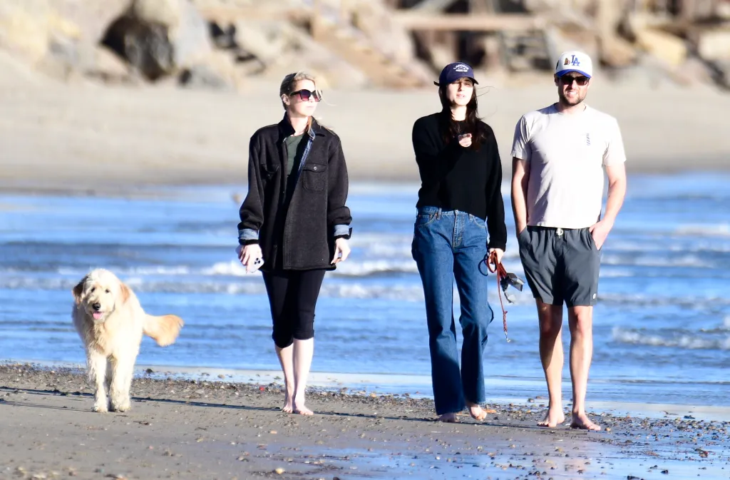 Romy Reiner, Jake Reiner, Jake Reiner's girlfriend, and a friend walking barefoot on the beach with a dog.