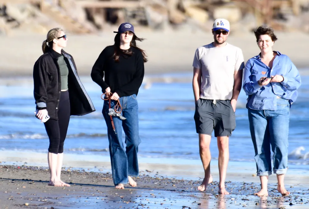 Romy Reiner and Jake Reiner with his girlfriend and a friend walking barefoot on the beach.
