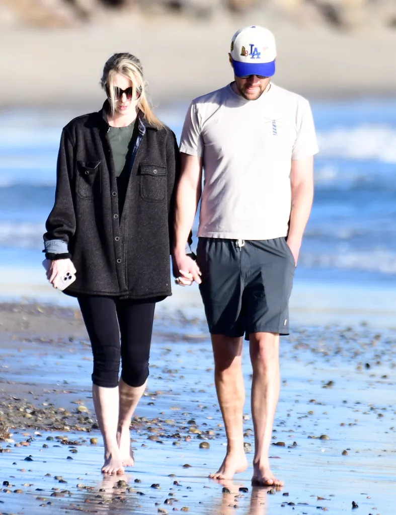 Romy Reiner and Jake Reiner's girlfriend walking barefoot on a beach.