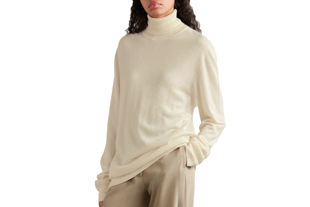 A woman wearing a cream-colored turtleneck sweater and beige pants.