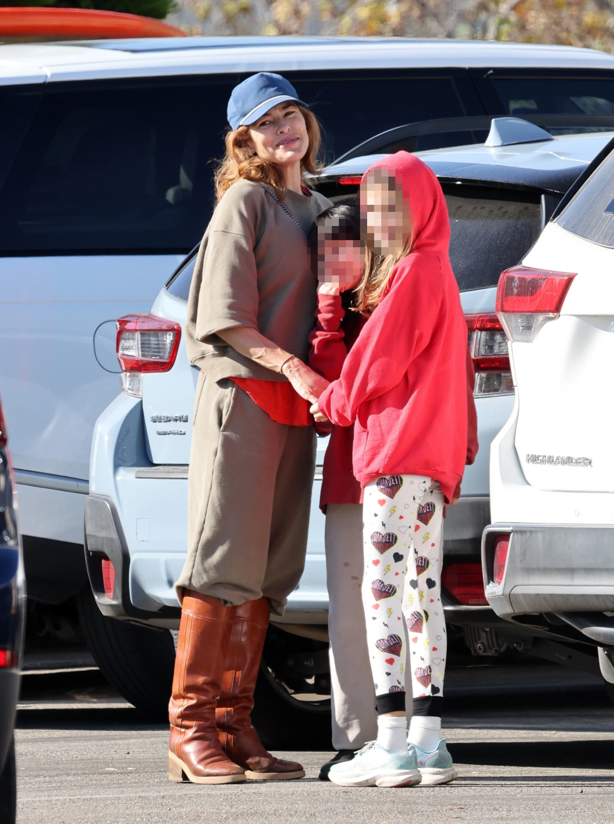Eva Mendes in a blue baseball cap and brown boots, holding hands with her daughters, Esmeralda and Amada.