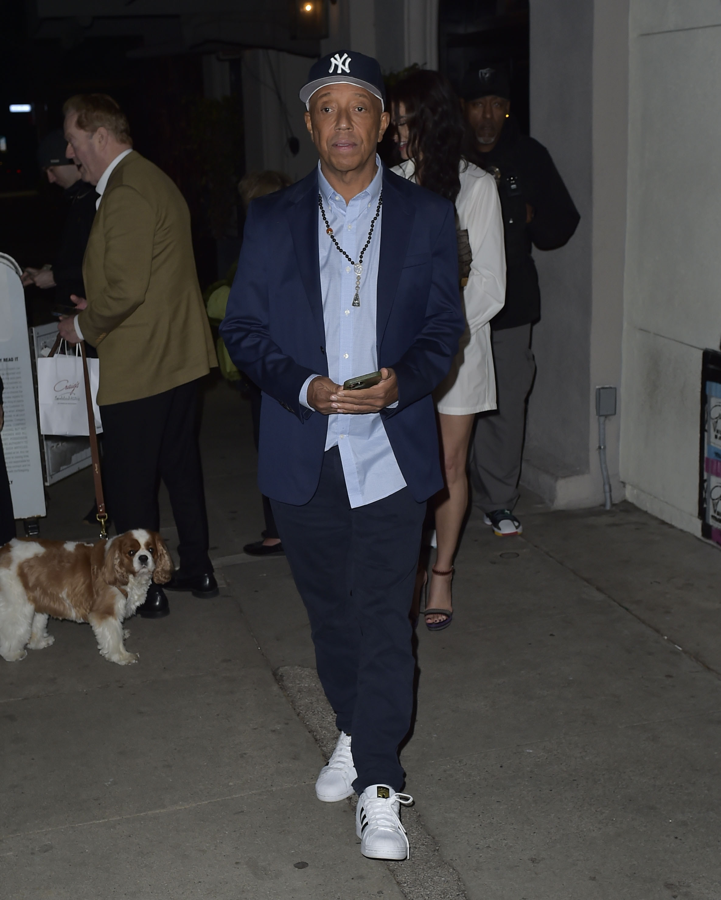 Russell Simmons in a blue blazer, light blue shirt, and baseball cap.