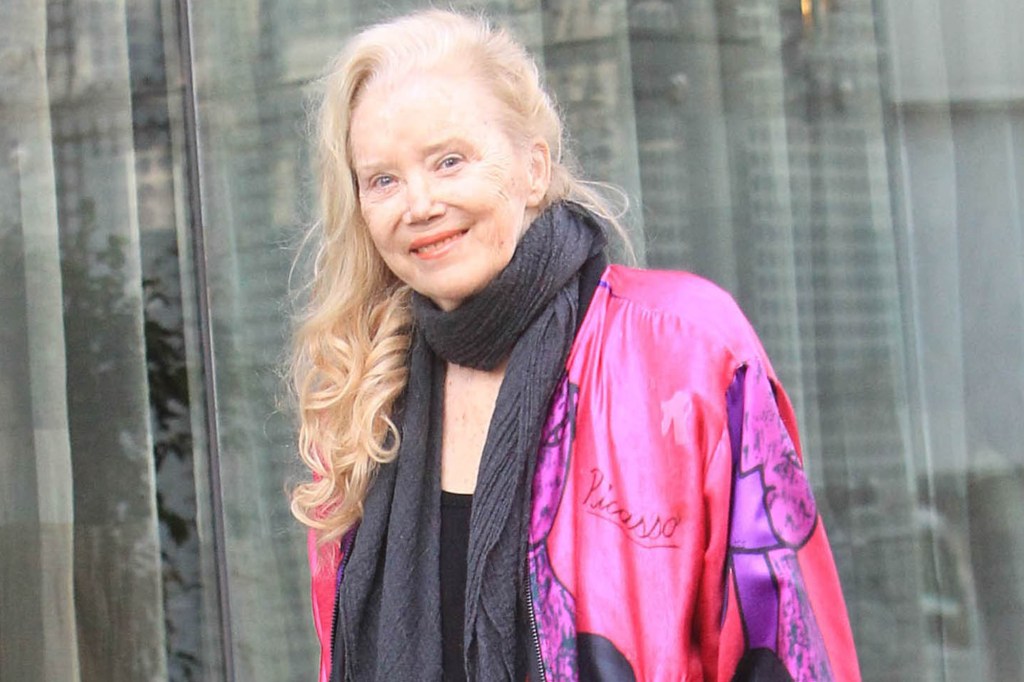 Sally Kirkland smiling while wearing a pink jacket with