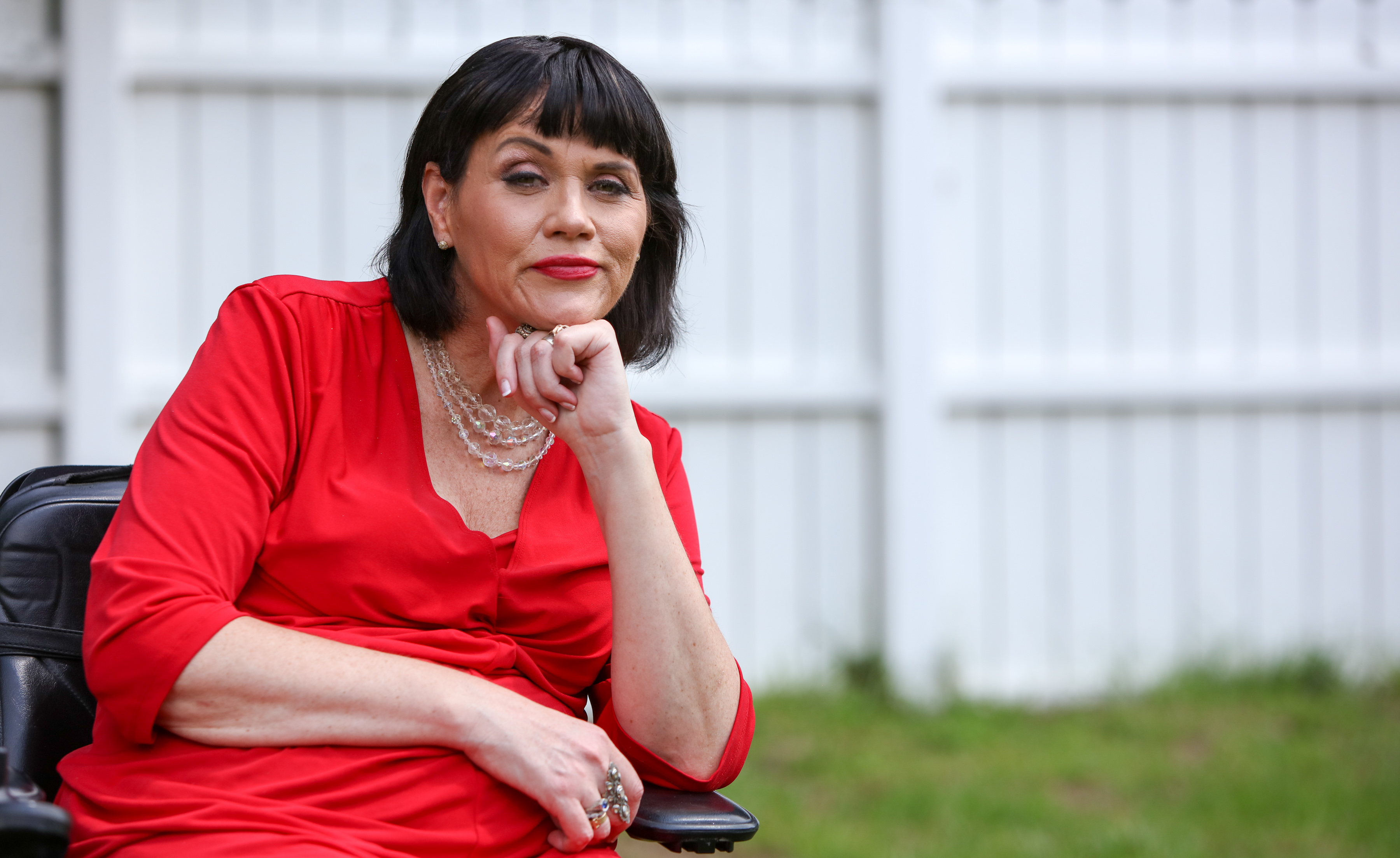 Samantha Markle, half-sister of Meghan Markle, in a red dress with a beaded necklace.