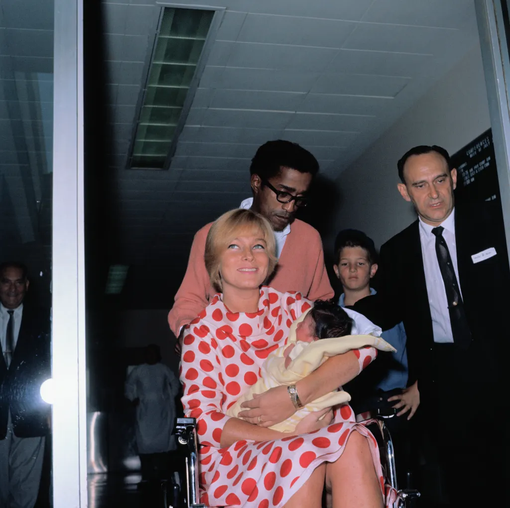Sammy Davis Jr. wheels his wife, May Britt, and their daughter, Tracey Davis out of Cedars of Lebanon Hospital after their daughter's birth.