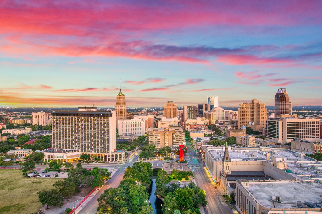 Aerial panorama of the San Antonio, Texas skyline at sunset.