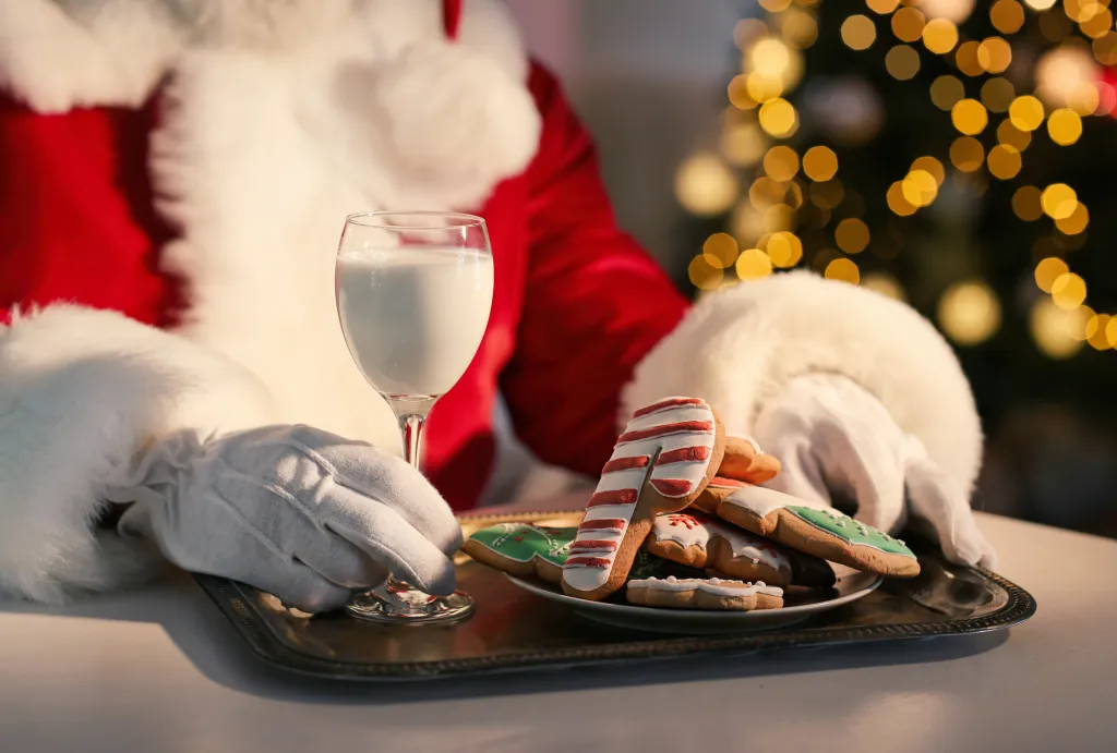 Santa Claus wearing white gloves with a tray of milk and cookies.