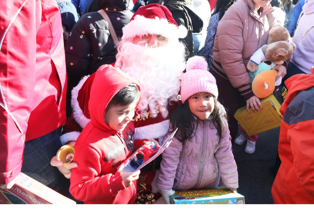 Santa Claus giving toys to children at a sleigh ride and toy giveaway event.