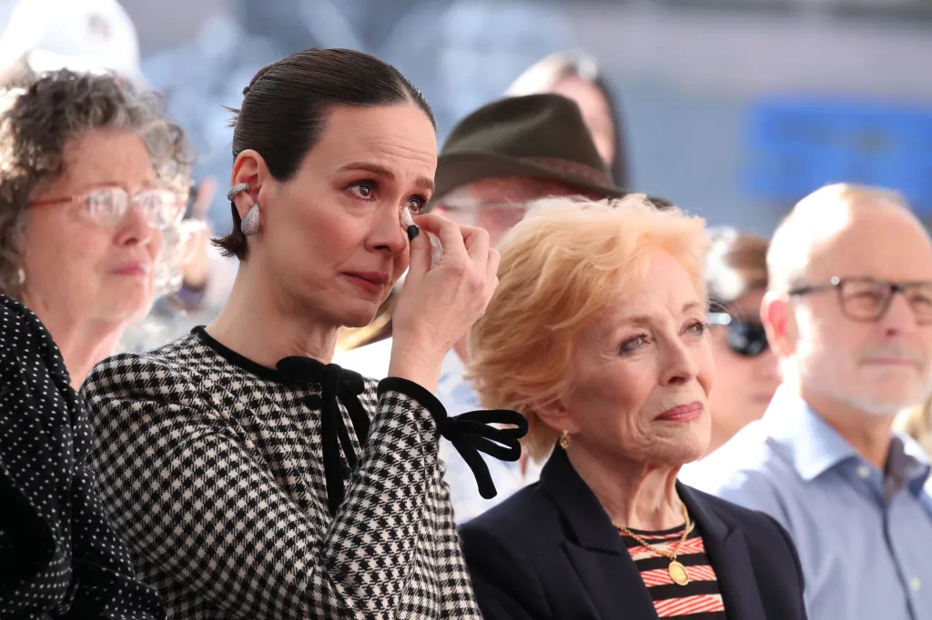 Sarah Paulson wipes a tear from her eye, sitting next to Holland Taylor.