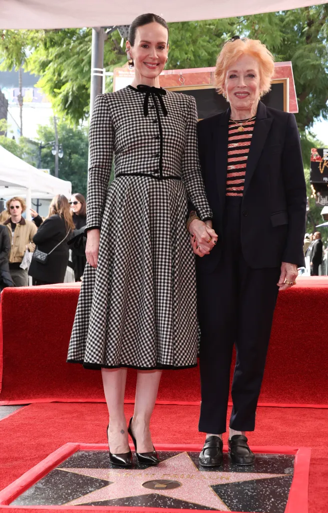 Sarah Paulson and Holland Taylor stand on the Hollywood Walk of Fame, holding hands, with Paulson's star visible at their feet.