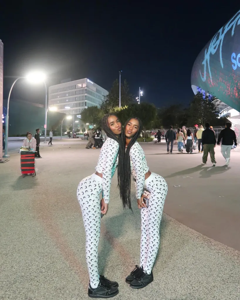 D'Lila and Jessie Combs in matching white outfits with black crescent moon patterns.