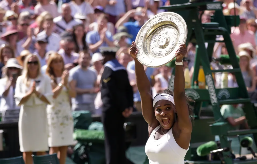 Serena Williams holds up the Wimbledon trophy and celebrates her victory.