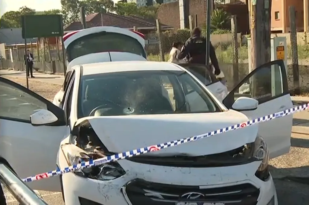 A white car with doors and trunk open, surrounded by police tape.