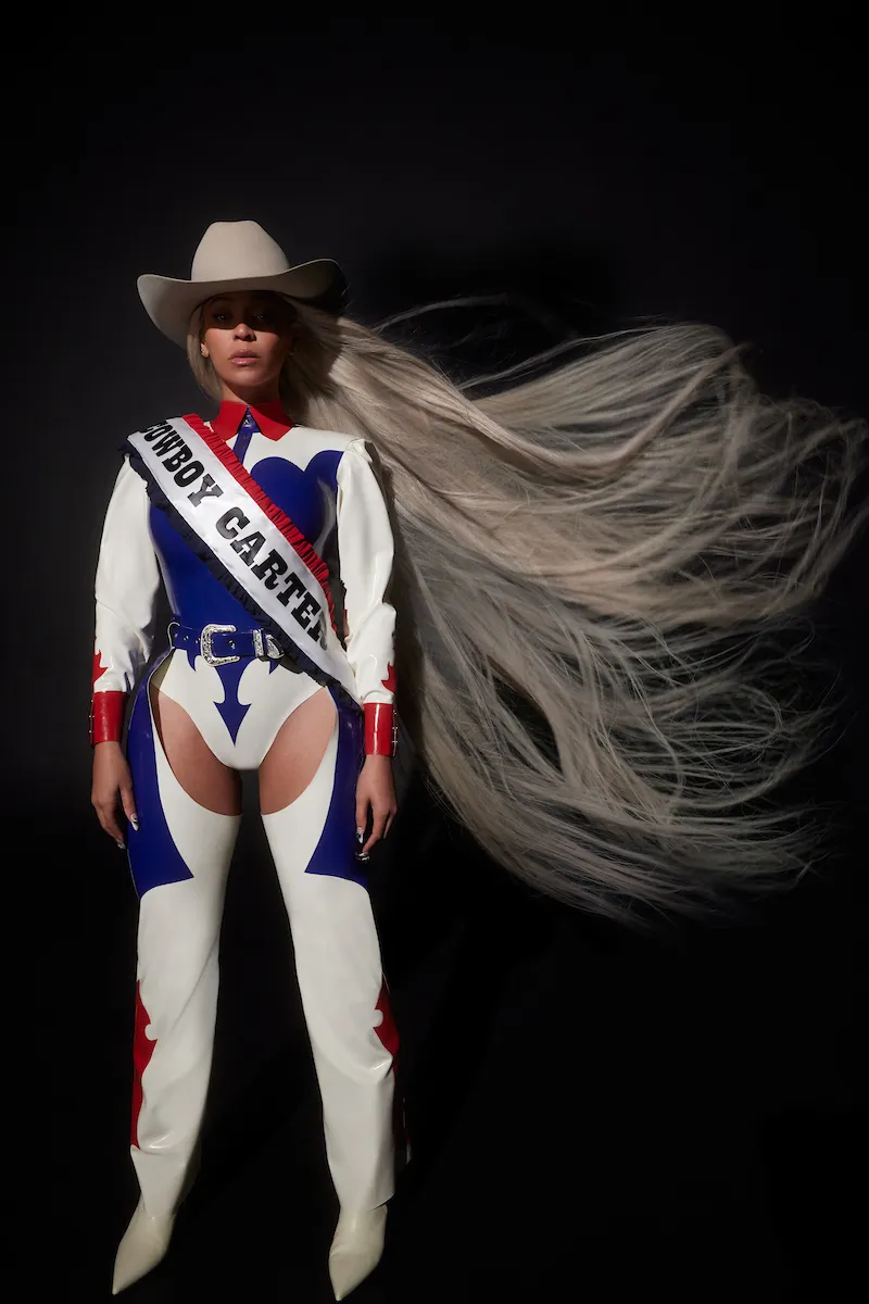 Beyoncé in a red, white, and blue latex cowboy outfit, wearing a 