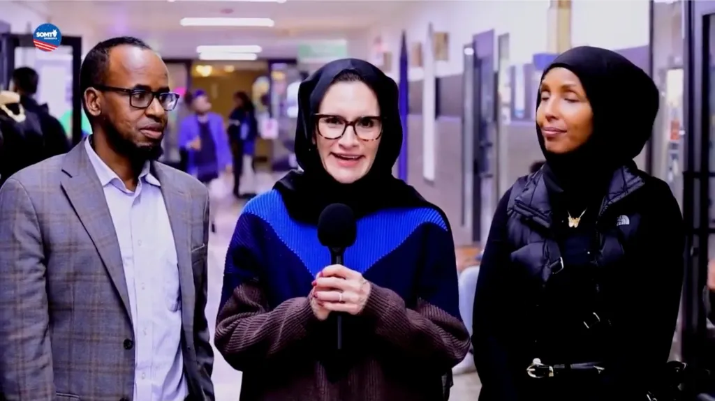 Minnesota Lt. Gov. Peggy Flanagan, wearing a hijab and holding a microphone, with a man and woman.