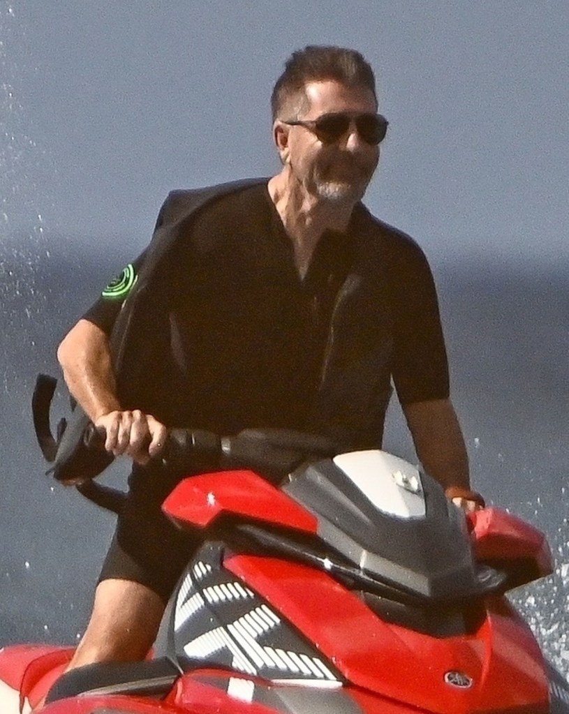 Simon Cowell riding a red jet ski.